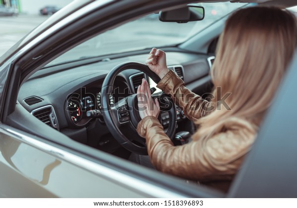 Woman driving a car. He presses signal on steering\
wheel of car, gesture with his fist, aggression, discontent,\
accident incident, scandal scream, angry driver in motion in summer\
spring autumn city