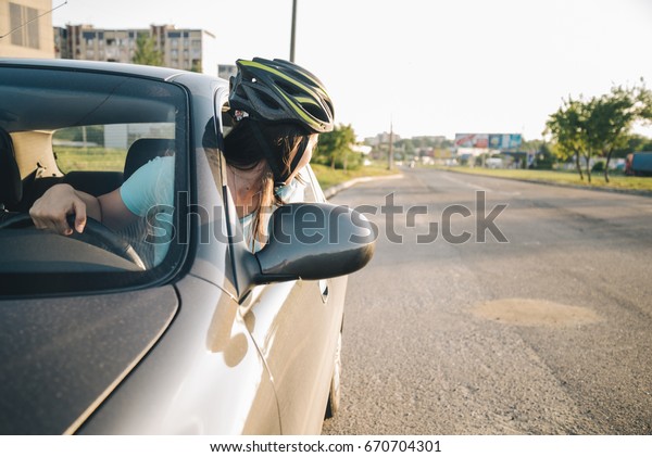 woman driving car in helmet with horror on her\
face, learning driving