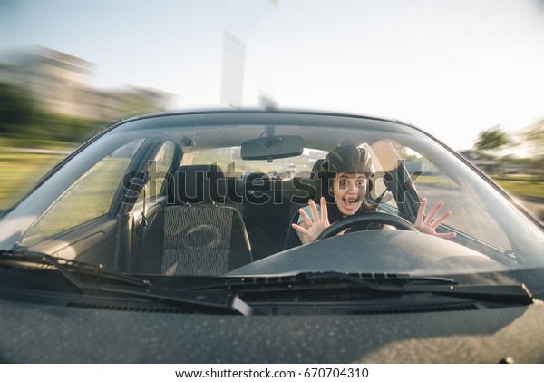 woman driving car in helmet with horror on her
face, learning driving