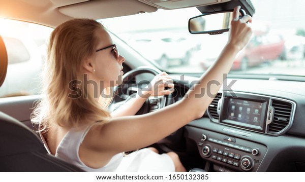 A\
woman driving a car, looking in the rearview mirror, reversing,\
parking shopping center, driving a car into the garage. Summer girl\
in a dress. Automatic transmission. Vehicle\
interior.