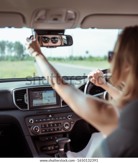A woman\
driving a car, looking in rearview mirror, reversing, parking at a\
shopping center, driving a car into garage. Summer girl in a dress.\
Automatic transmission. Vehicle\
interior.