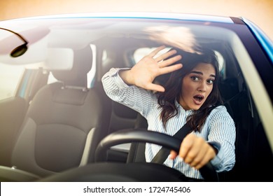 The woman driving the car in a panic. The lady urgently brakes in the car or grabbed the wheel frightened. Front pose of a young woman being scared and surprised while driving the car.
