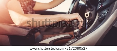 Woman driving a car and shifting gears on the gearbox. Concept of vacation and travel.