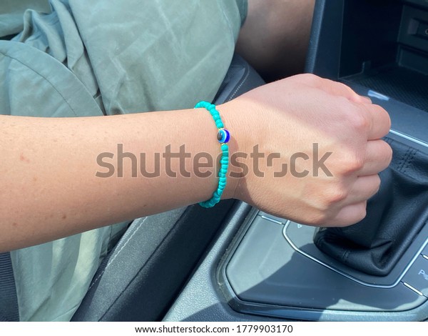 Woman driving car shifts gears and has an ornament
on her wrist