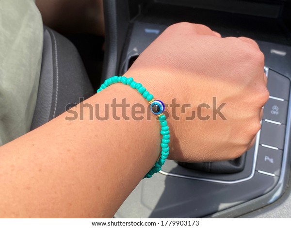Woman driving car shifts gears and has an ornament\
on her wrist