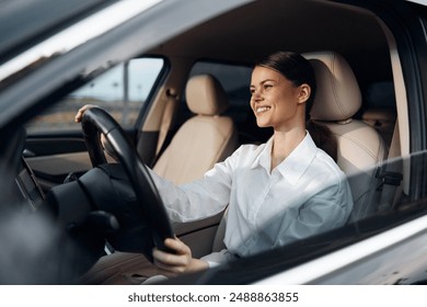 Woman driving car, smiling, hand on steering wheel a woman is seated in the driver's seat of a vehicle, her hand resting on the steering wheel, with a cheerful smile on her face, capturing a moment of