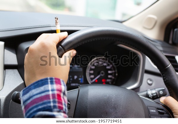 Woman driving a\
car smokes, focus on\
cigarettes