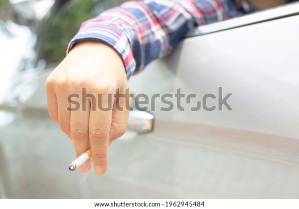Woman driving a\
car smokes, focus on\
cigarettes