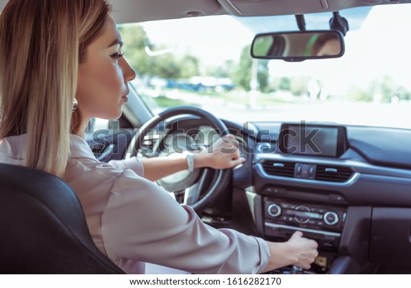 Woman\
driving a car, in summer in parking lot near a shopping center.\
Reversing, interior of car, looking in the side view mirror.\
Automatic transmission. Parking in the\
garage