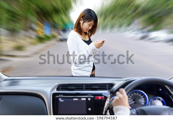 Woman driving fast and dangerous\
driving. woman using smart phone will be hit by a car on the\
road