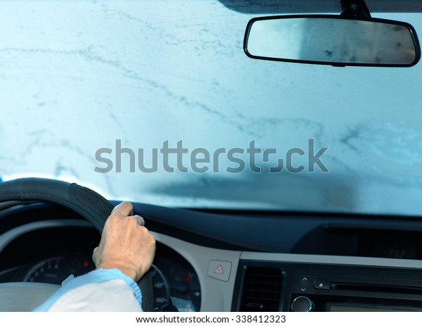Woman driving with frozen windshield.  Driver\
insurance concept.