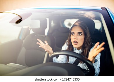 Woman is driving her car very aggressive and gives gesture with her fist. Angry female driver. Negative human emotions face expression. Furious woman stucked in traffic jam