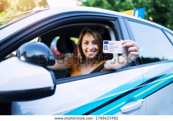 Woman with driving license. Driving\
school. Young beautiful woman successfully passed driving school\
test. Female smiling and holding driver\'s\
license.