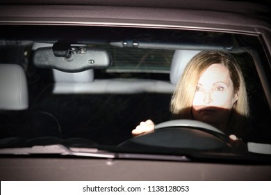 A Woman Is Driving At Night; The Oncoming Car Has Its High Beam Headlights On.