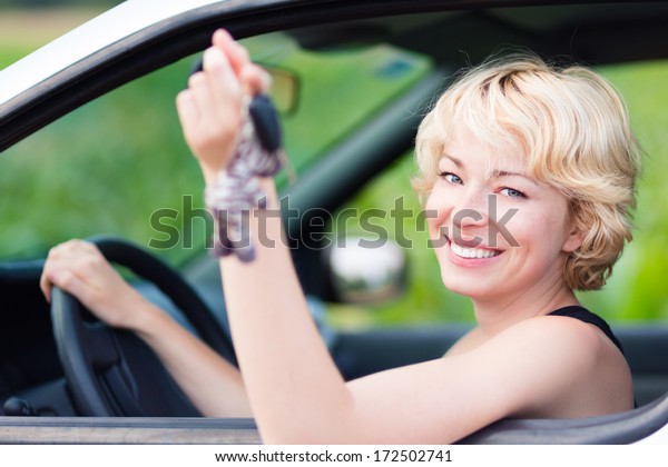 Woman, driving showing car keys out the window.
Young female driving happy about her new car or drivers license.
Caucasian model.