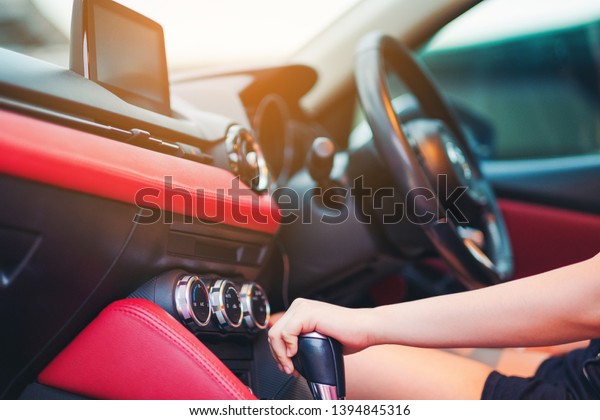 Woman driving, using a manual transmission stick\
shift. close up of woman shifting gears on gearbox and driving car\
selective focus on hand.