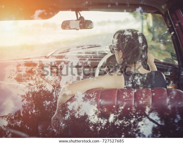 Woman driving vintage car. Retro style\
image of happy smiling young woman in old pink car going on road\
trip on sunny spring or summer day.  Vintage\
style