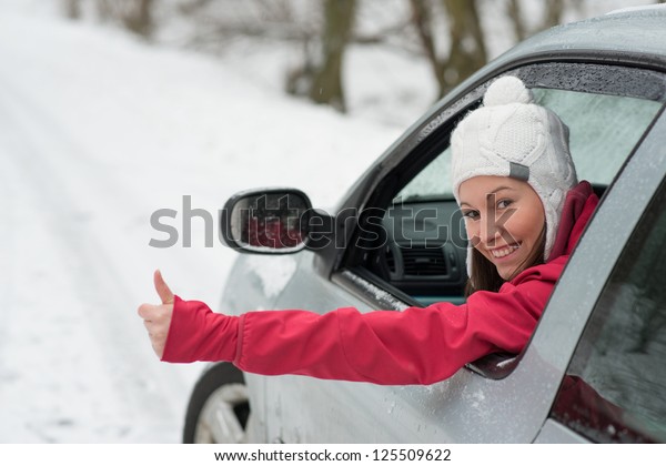 Woman driving in winter on snow covered slippery\
road in forest
