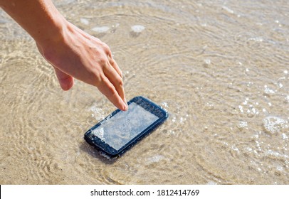 The Woman Dropped Her Smartphone Into The Sea. Lost Mobile Phone On A Sandy Beach.