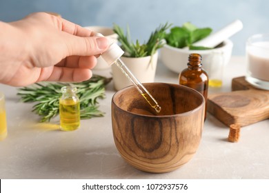 Woman dropping essential oil into bowl