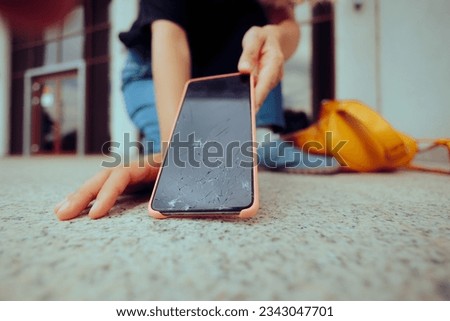 
Woman Dropping her Phone on the Floor Breaking the Display. Stressed person picking up the broken smartphone she dropped 
