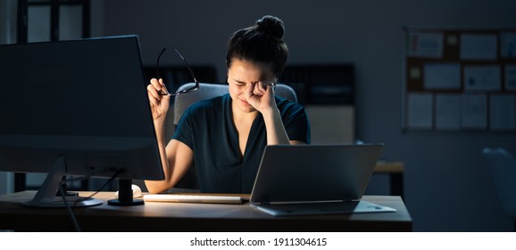 Woman With Dry Tired Eyes Working Late At Night Using Computer In Office