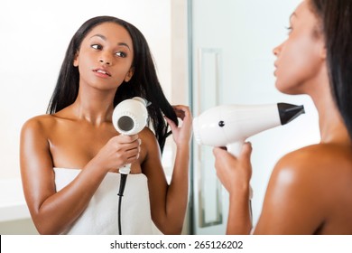 Woman Drying Hair. Rear View Of Beautiful Young African Woman Washing Hands In Bathroom And Looking At The Mirror 