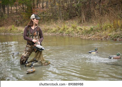 Woman Duck Hunter In Pond Wearing Camo Waders