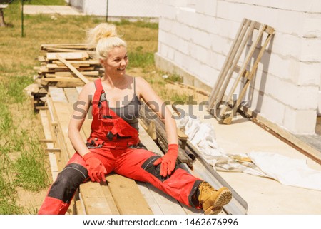 Woman in dungarees relaxing after hard work on construction site. Young female lying outdoor taking a break