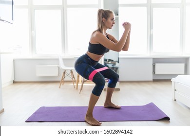 Woman during her fitness workout at home with rubber resistance band - Shutterstock ID 1602894142
