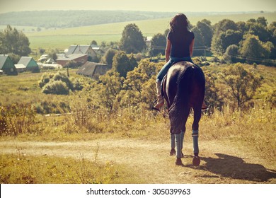 Woman during horseback riding the summer in the countryside.