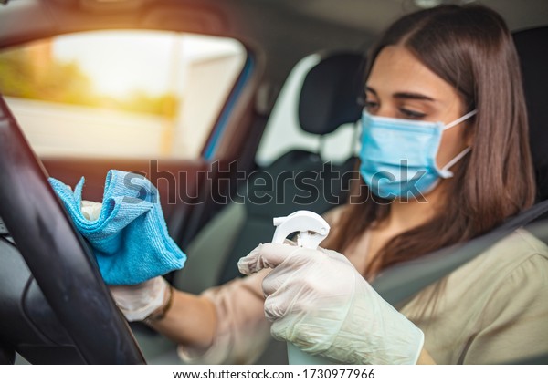 Woman during\
pandemic isolation at city, she is in car and disinfect. Woman in\
car disinfecting steering wheel. Adult Woman Disinfecting Car Dash\
Board with Antiseptic and Wet\
Wipe