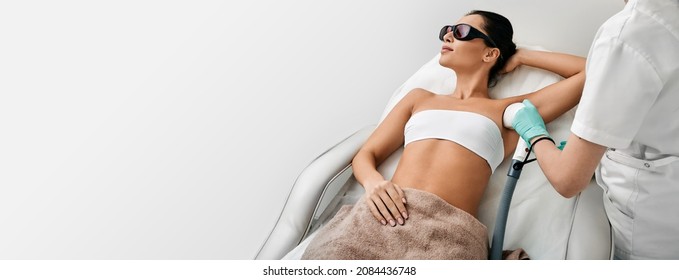 Woman during underarm laser hair removal and armpit laser epilation at beauty center. Laser epilation concept, web banner with space for text