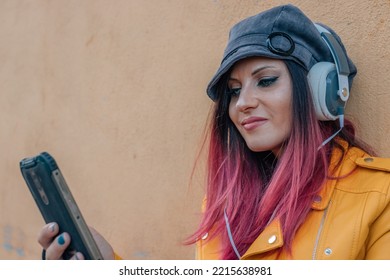 Woman With Dyed Red Hair With Headphones And Mobile Phone Outdoors