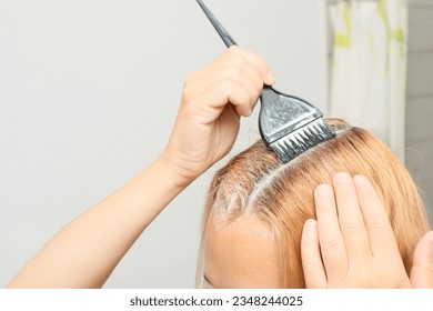 Woman dyeing her hair in front of mirror at home. Closeup woman hands dyeing hair using a black brush. - Powered by Shutterstock