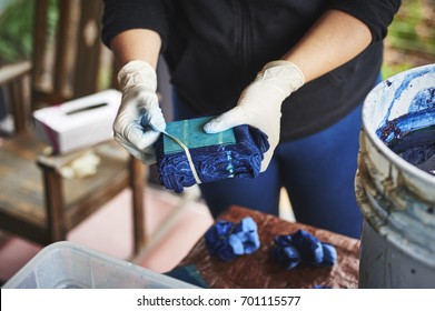 A Woman Dying Fabric With Indigo Dye.