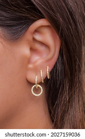Woman ear with mulriple piercings wearing beautiful earrings with zirconia- details capture