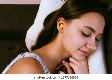 A Woman In Earplugs Sleeps On The Bed