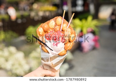 woman eat a waffle ice cream with strawberries at a street