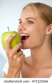 Woman Eating Apple. Closeup Portrait Of Beautiful Happy Woman With Perfect Smile And Healthy White Teeth Biting Organic Green Apple. Dental Health, Diet Food, Nutrition Concepts. High Resolution Image
