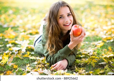 Woman Eating Apple Outdoors In Autumn