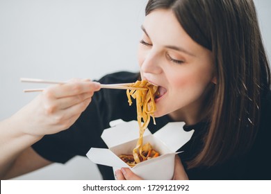 Woman eating asian chineese food noodles with vegetables in wok box using chopsticks. Food delivery. Take away lunch. - Powered by Shutterstock