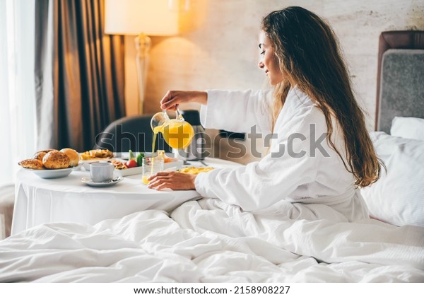 Woman eating breakfast in the hotel room. Room\
service breakfast in hotel room.\

