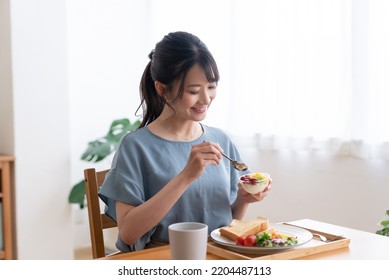 woman eating breakfast in the living room - Powered by Shutterstock