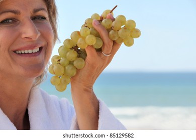 Woman Eating A Bunch Of Grapes By The Sea