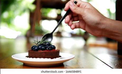 Woman Eating Cake In A Cafe. Blueberry Cheese Tart. Beautiful Tasty Dessert On The Table. Enjoy Fresh Baked Dessert In Coffee Shop. Closeup Shot Of Little Sweet Decorative Cake.