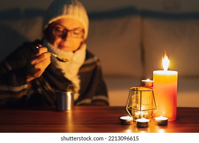 Woman Eating Canned Food By Candlelight. Electricity And Gas Outages In Winter. Power Cut. Grain Effect, Selective Focus.	