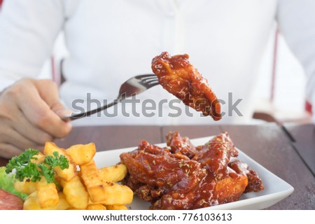 Woman eating chicken wing and potato chips.