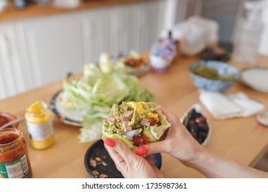 Woman Eating A Chicken Wrap Holding It With Both Hands At Home. Fresh Lettuce Wraps Delicious Option For Lunch Or Dinner. Healthy Lettuce