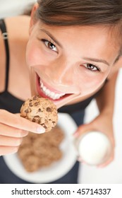Woman eating cookie and drinking milk. Cute adorable beautiful young female model.